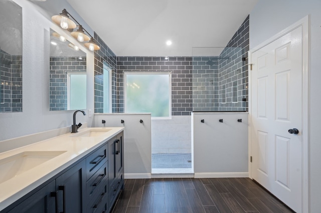 bathroom with vanity, vaulted ceiling, and tiled shower