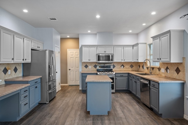 kitchen with appliances with stainless steel finishes, dark hardwood / wood-style flooring, a kitchen island, and sink