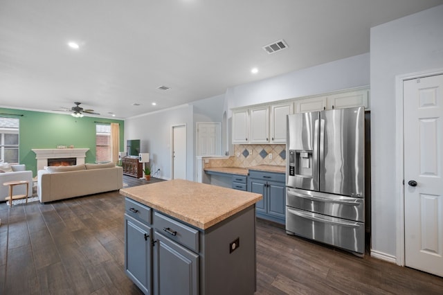 kitchen featuring ceiling fan, dark wood-type flooring, a kitchen island, stainless steel refrigerator with ice dispenser, and white cabinets