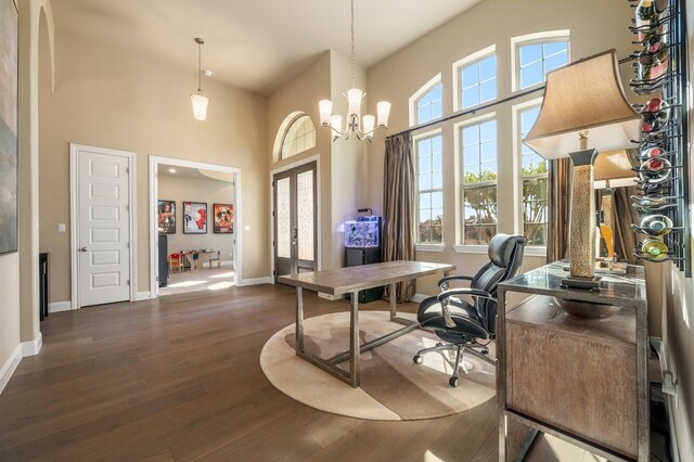 office area with a towering ceiling, dark wood-type flooring, a notable chandelier, and french doors