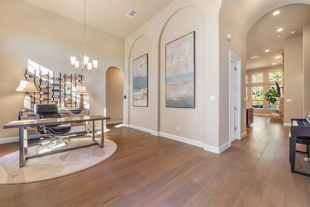 home office featuring a notable chandelier, a high ceiling, and hardwood / wood-style floors