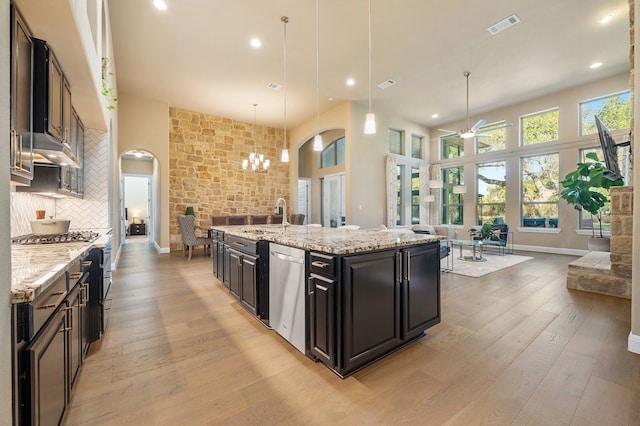 kitchen featuring a large island, appliances with stainless steel finishes, tasteful backsplash, decorative light fixtures, and light wood-type flooring