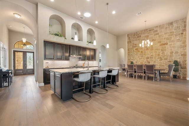 465 Linden Loop, Driftwood, TX 78619 - kitchen with a chandelier, arched walkways, wood-type flooring, an island with sink, and pendant lighting