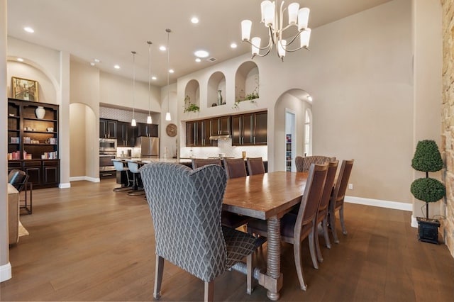 dining area with a high ceiling, a chandelier, and hardwood / wood-style flooring