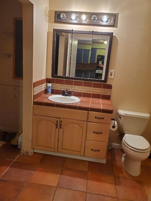 bathroom with backsplash, tile patterned floors, vanity, and toilet