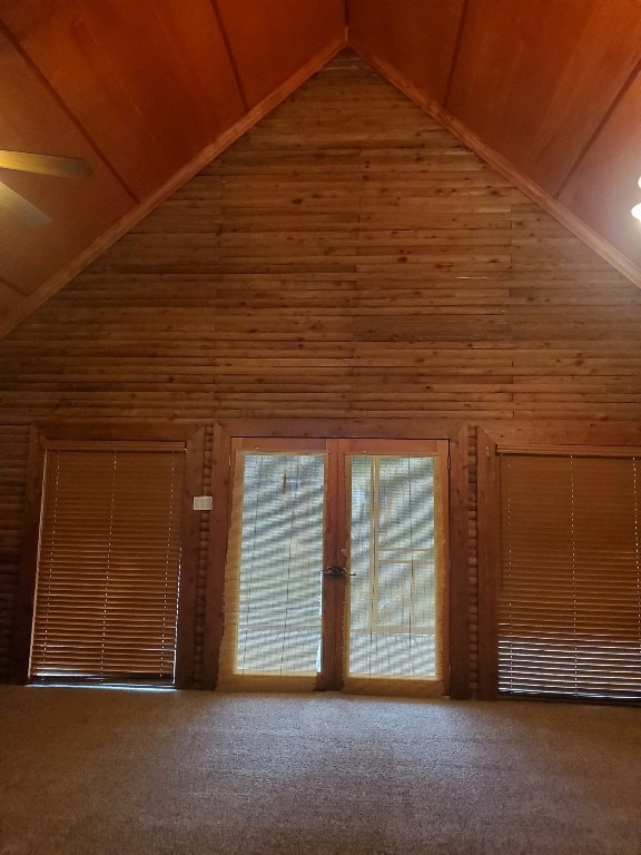 additional living space featuring carpet, wood walls, and high vaulted ceiling