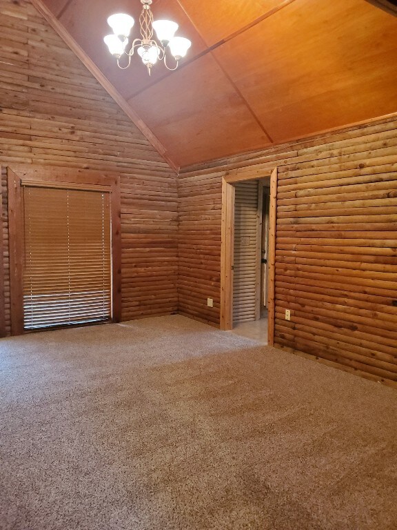 spare room with carpet, high vaulted ceiling, and an inviting chandelier