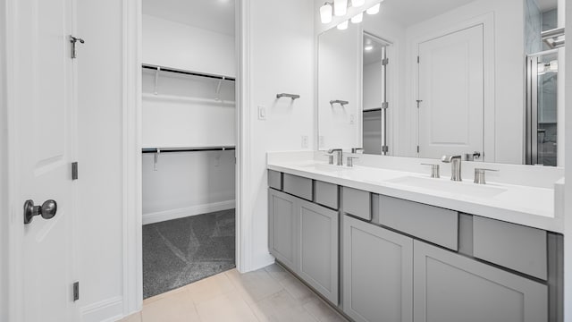 full bathroom featuring double vanity, a spacious closet, baseboards, and tile patterned flooring