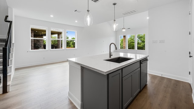 kitchen featuring a sink, gray cabinetry, dishwasher, light wood-style floors, and recessed lighting