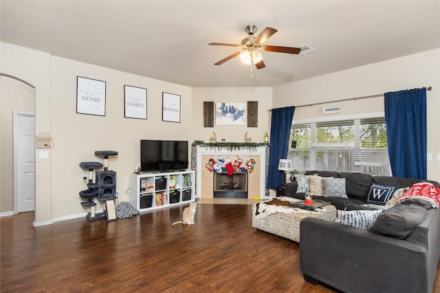 living room featuring dark hardwood / wood-style floors, ceiling fan, and a fireplace