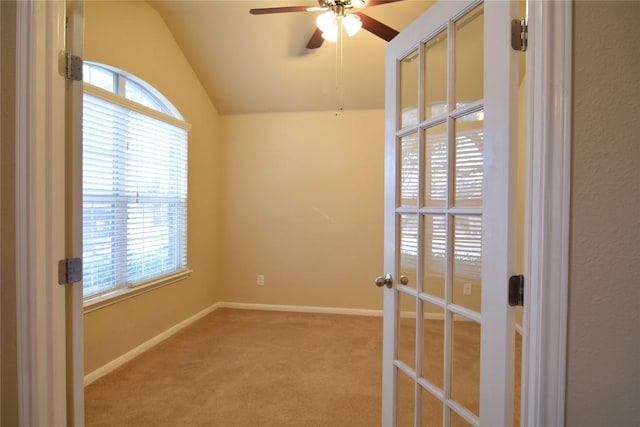 carpeted empty room featuring ceiling fan, lofted ceiling, and french doors