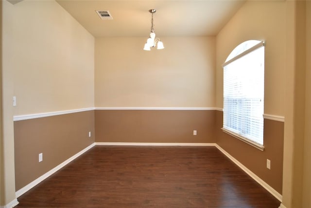 unfurnished room featuring a chandelier and dark hardwood / wood-style flooring