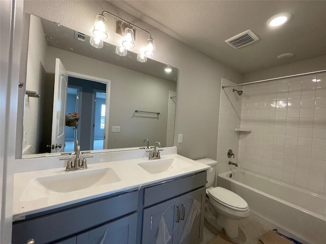 full bathroom featuring tiled shower / bath, vanity, and toilet