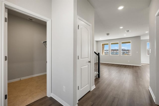 hall featuring dark wood-style floors, recessed lighting, visible vents, and baseboards