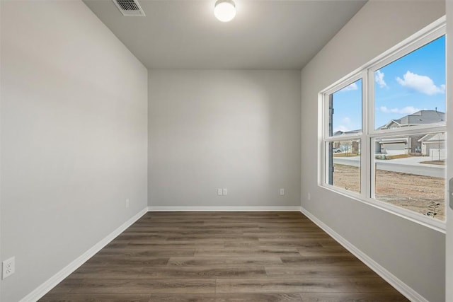 unfurnished room featuring baseboards, visible vents, and dark wood finished floors