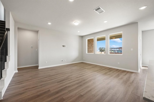 empty room with recessed lighting, wood finished floors, visible vents, and stairs