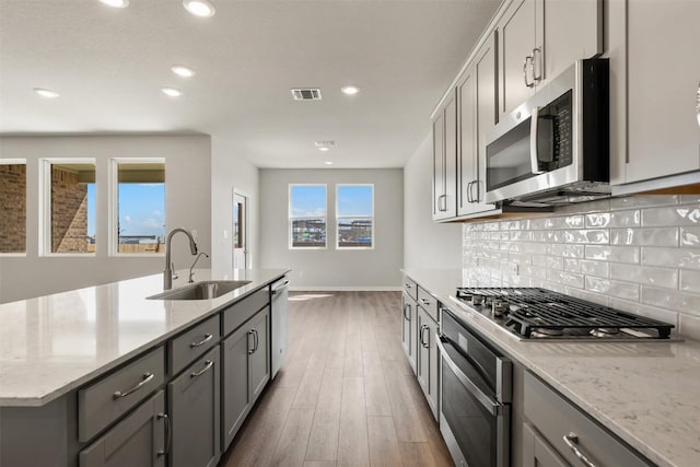 kitchen featuring stainless steel appliances, a sink, visible vents, gray cabinets, and backsplash