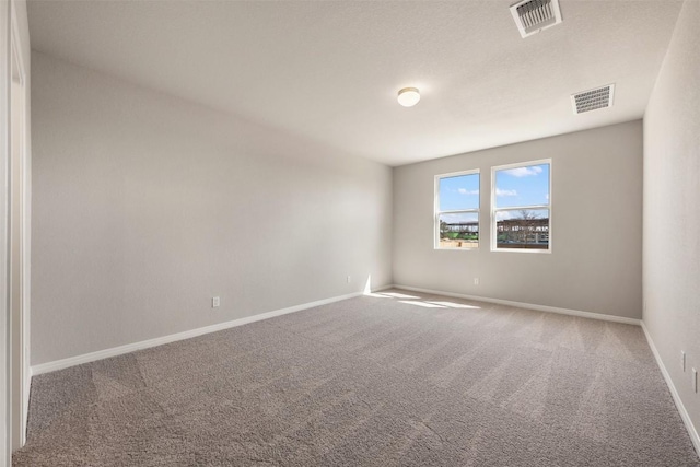 carpeted spare room with visible vents and baseboards