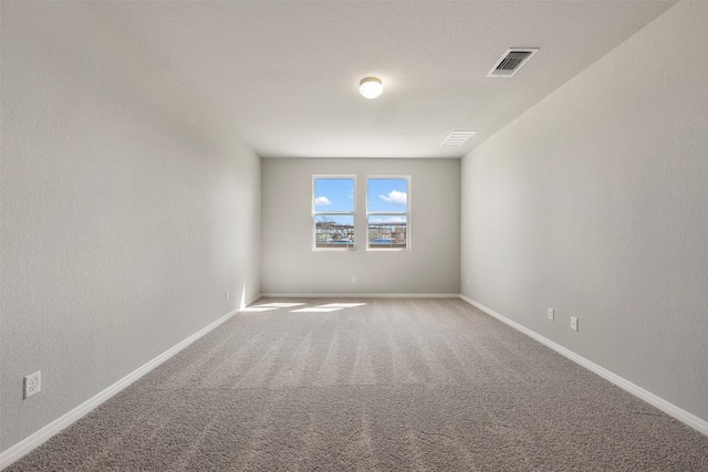 carpeted spare room with visible vents and baseboards