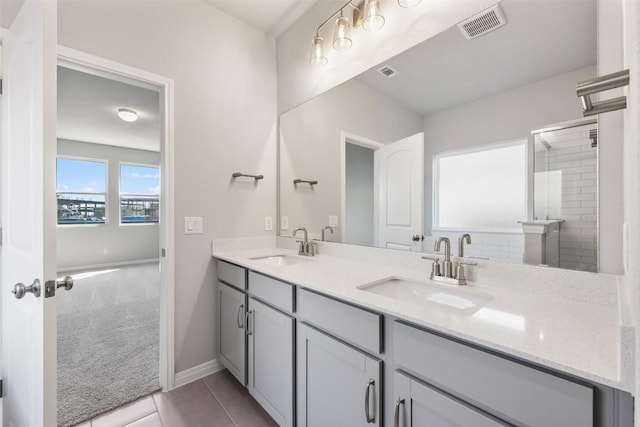 bathroom featuring double vanity, a sink, visible vents, and baseboards