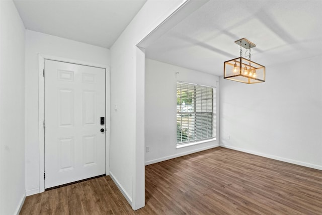 entryway with dark wood-type flooring and a chandelier