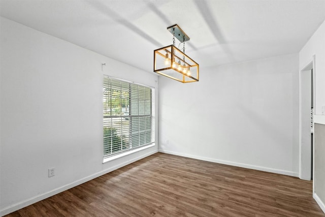 unfurnished dining area with an inviting chandelier and dark hardwood / wood-style flooring