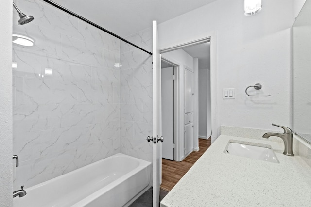 bathroom with tiled shower / bath, hardwood / wood-style floors, and vanity