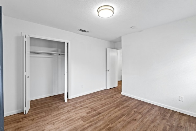 unfurnished bedroom with hardwood / wood-style flooring, a textured ceiling, and a closet