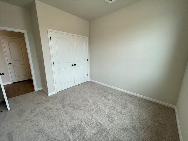 unfurnished bedroom with light colored carpet and a closet