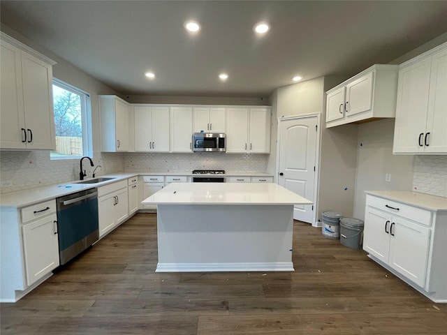 kitchen with appliances with stainless steel finishes, dark hardwood / wood-style flooring, white cabinetry, and a kitchen island