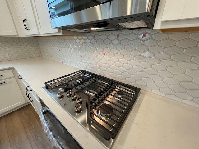 kitchen with backsplash, dark wood-type flooring, stainless steel appliances, and white cabinetry