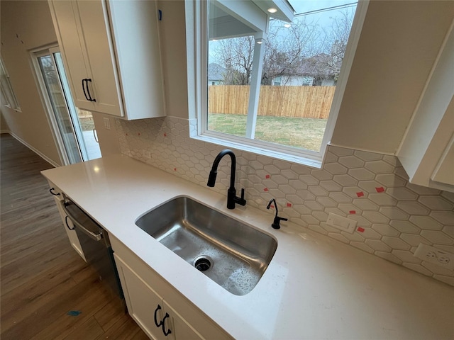 kitchen with white cabinetry, decorative backsplash, dark hardwood / wood-style floors, sink, and dishwashing machine