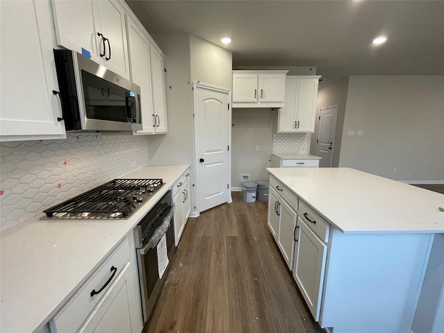 kitchen featuring a kitchen island, decorative backsplash, stainless steel appliances, white cabinets, and dark hardwood / wood-style flooring