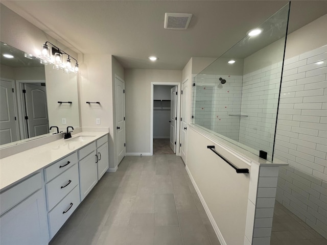 bathroom featuring a tile shower, tile patterned floors, and vanity