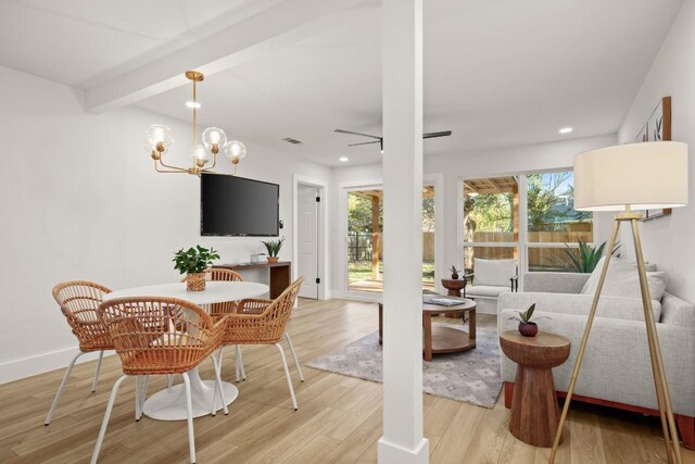 living room with beamed ceiling, light hardwood / wood-style floors, and ceiling fan with notable chandelier