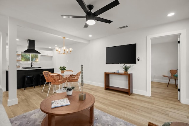 living room with sink, ceiling fan with notable chandelier, and light wood-type flooring