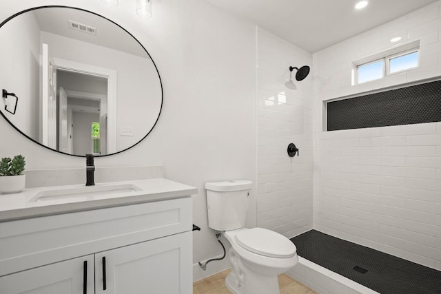 bathroom featuring tile patterned floors, toilet, vanity, and tiled shower