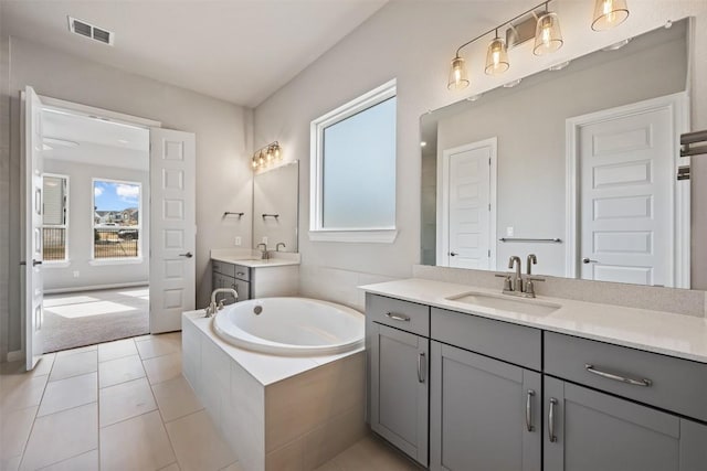 bathroom featuring tile patterned flooring, vanity, and a relaxing tiled tub