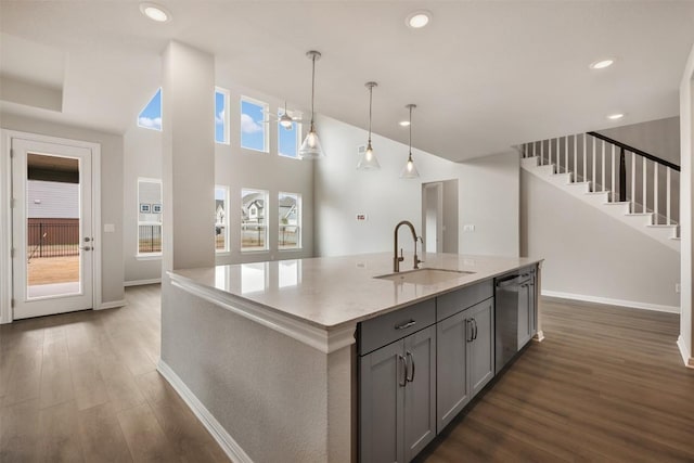 kitchen featuring sink, dishwasher, gray cabinetry, hanging light fixtures, and an island with sink