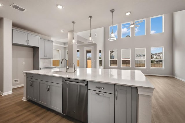 kitchen with sink, gray cabinets, hanging light fixtures, light stone countertops, and stainless steel dishwasher