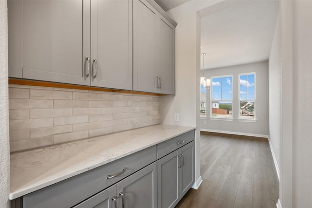 interior space featuring gray cabinetry, dark hardwood / wood-style flooring, tasteful backsplash, and light stone countertops