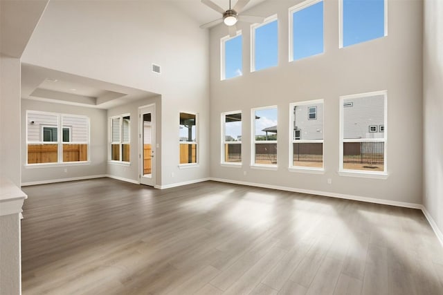 unfurnished living room with ceiling fan, dark hardwood / wood-style floors, and a raised ceiling