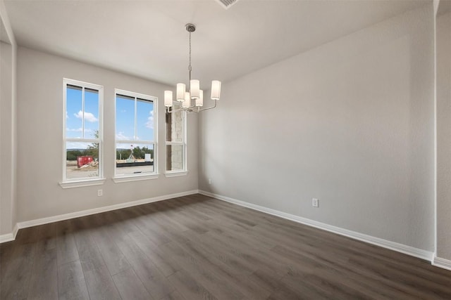 spare room featuring dark wood-type flooring and a chandelier