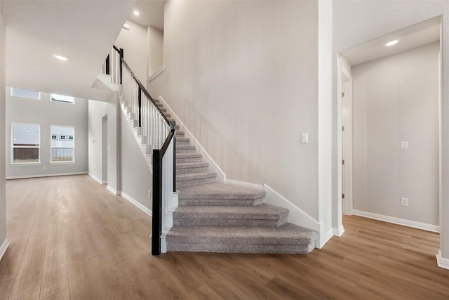 stairs featuring wood-type flooring and a high ceiling