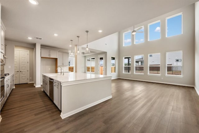 kitchen with sink, appliances with stainless steel finishes, white cabinets, a center island with sink, and decorative light fixtures