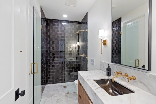 bathroom featuring a shower with door, vanity, and toilet