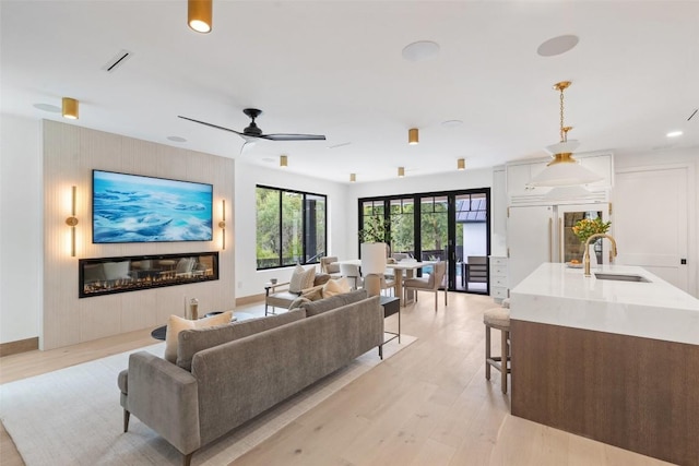 living room featuring sink, ceiling fan, and light hardwood / wood-style flooring