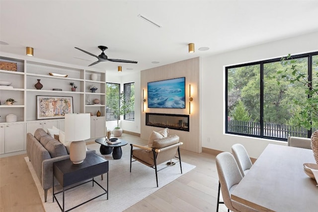 living room with a wealth of natural light, ceiling fan, and light wood-type flooring