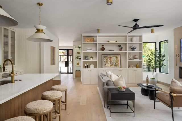 living room with ceiling fan, sink, and light hardwood / wood-style flooring