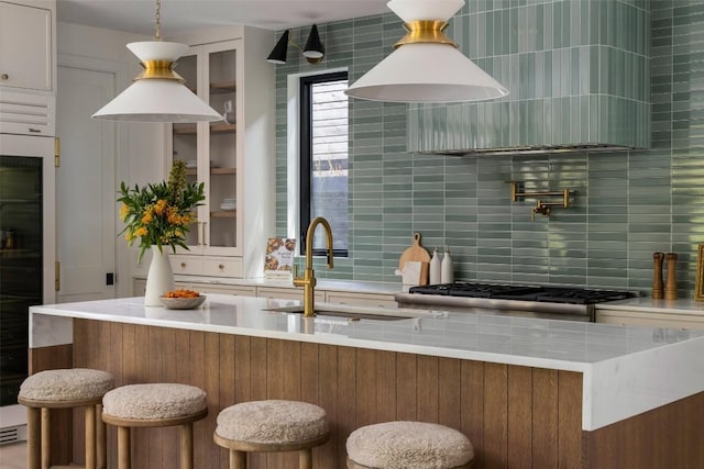 kitchen with sink, a breakfast bar area, white cabinets, decorative backsplash, and stove